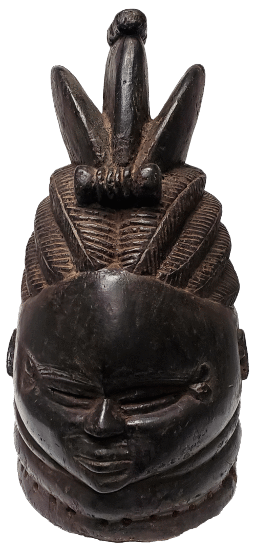 Dark wood carving of a stylized human head with intricate braided hair and a prominent crest, set against a white background.