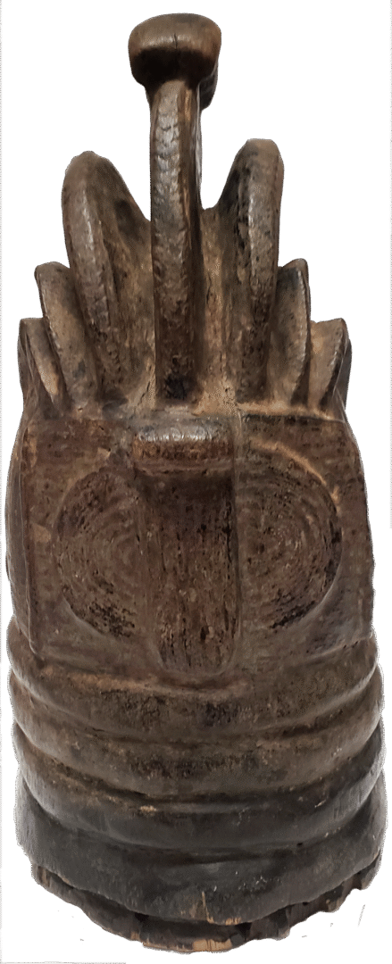 A weathered, dark wooden carving with a ribbed, cylindrical base and a prominent, arched loop handle at the top.