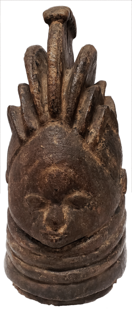 A dark, weathered bronze sculptural head featuring a stylized crest, prominent facial features, and rings around the neck.