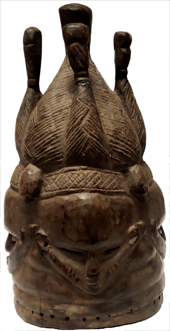 Carved wooden headpiece with multiple sculpted faces and an ornate, textured crown with vertical extensions.