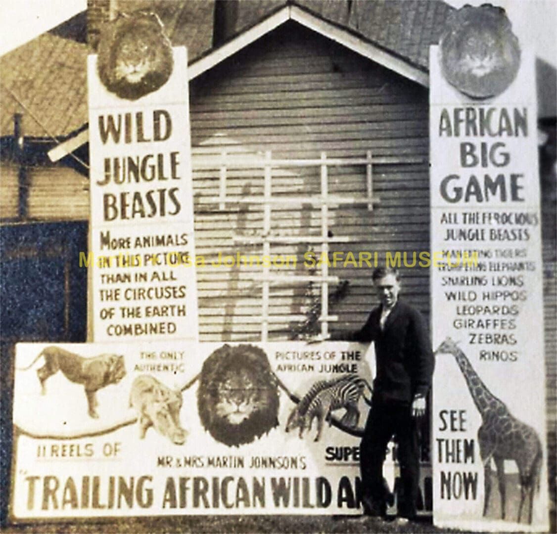 A man stands beside large, vintage promotional banners for the film