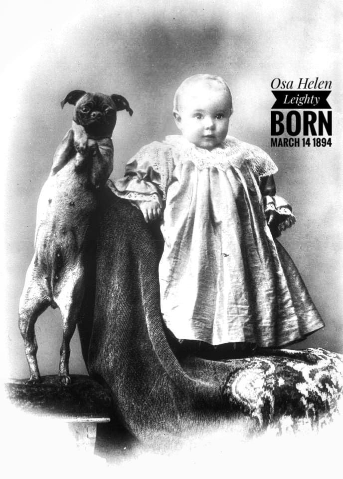 A black-and-white vintage portrait of a child in a dress standing next to a pug standing on its hind legs.