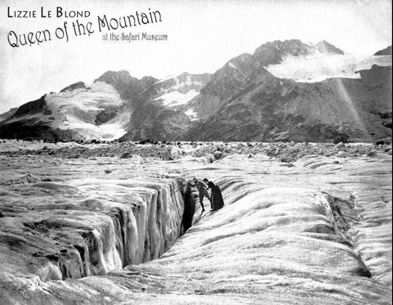 Black-and-white historical photo of Lizzie Le Blond standing by a deep glacier crevasse in a mountain landscape.