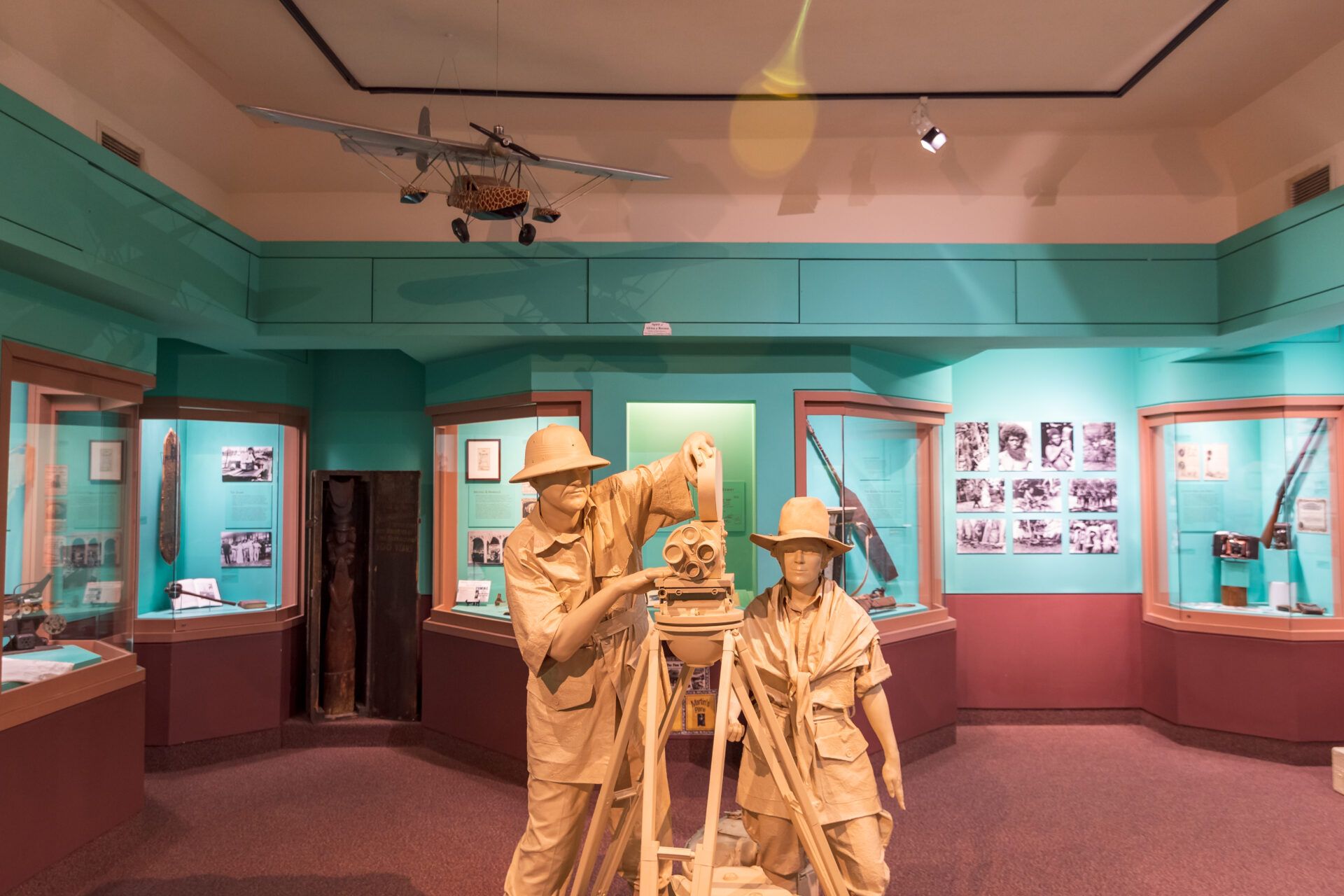 Museum exhibit featuring two mannequins in tan uniforms operating a tripod-mounted surveying tool.