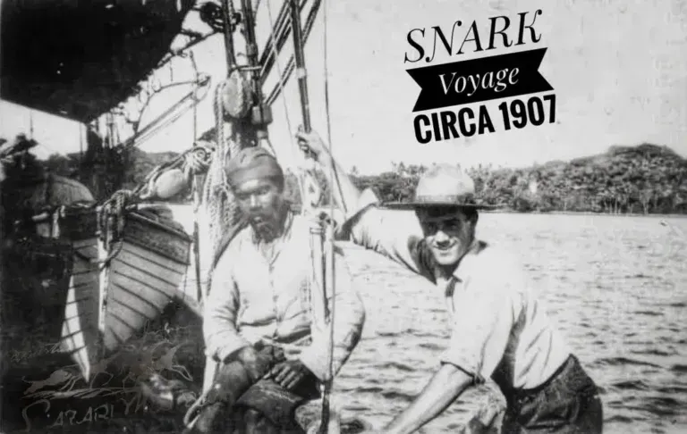 Two people sit on a boat during the Snark voyage circa 1907, with lush vegetation visible in the background.