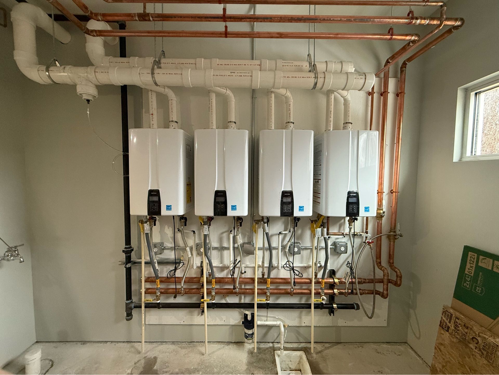 Wall-mounted white water heaters with copper piping in a utility room