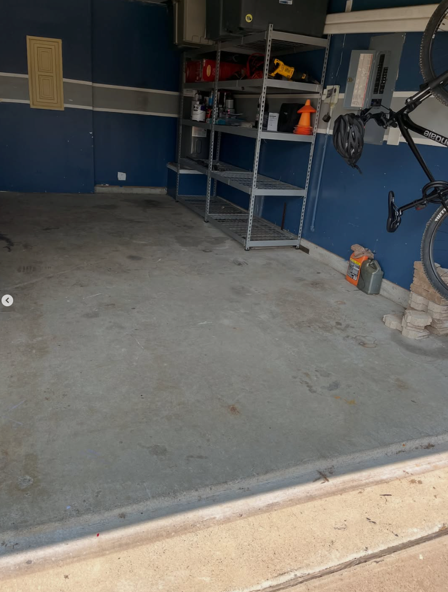 Empty garage with concrete floor, metal shelves, and bikes hanging on the right side.