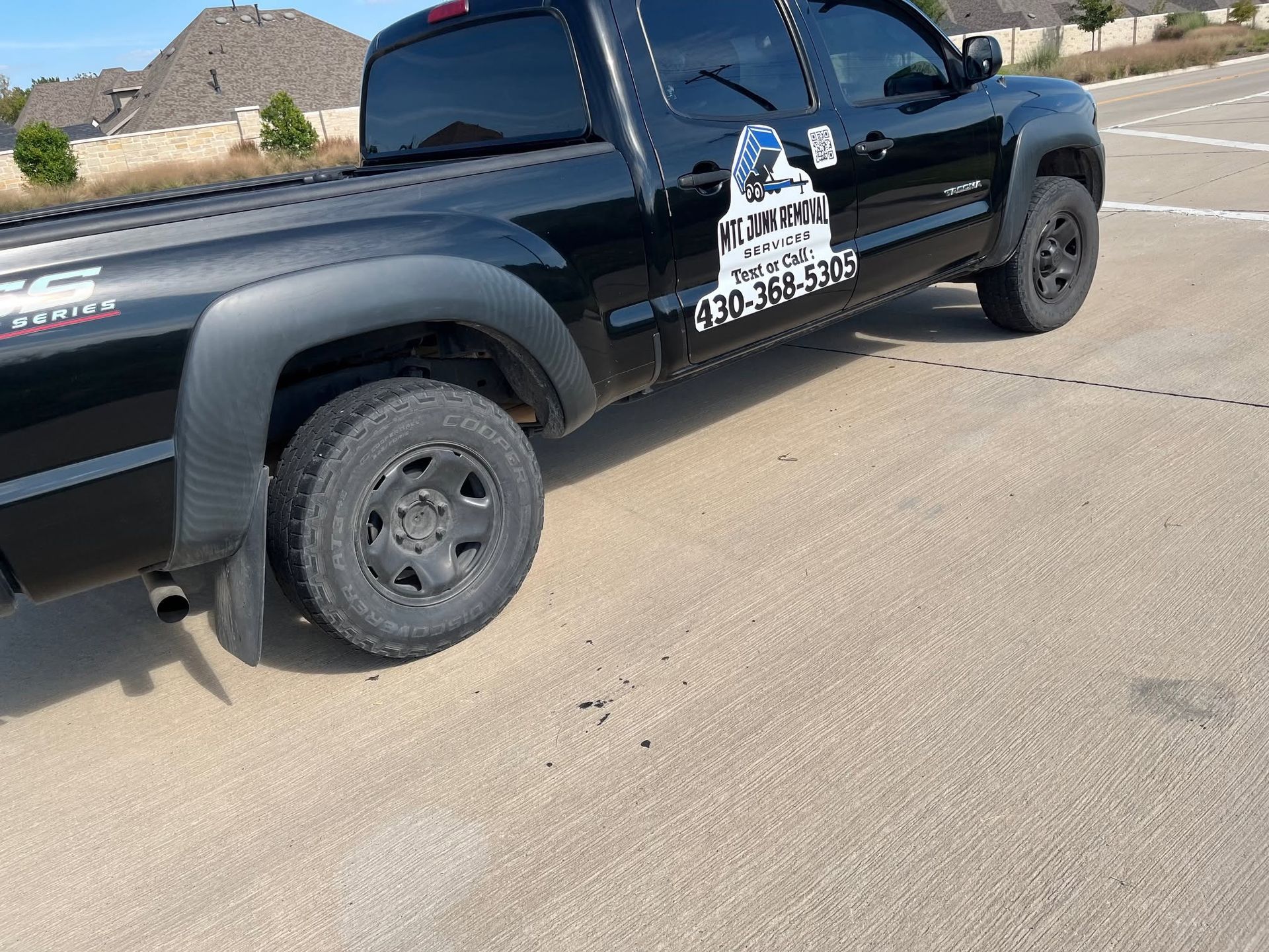 Black pickup truck parked on a sunlit road beside desert landscaping