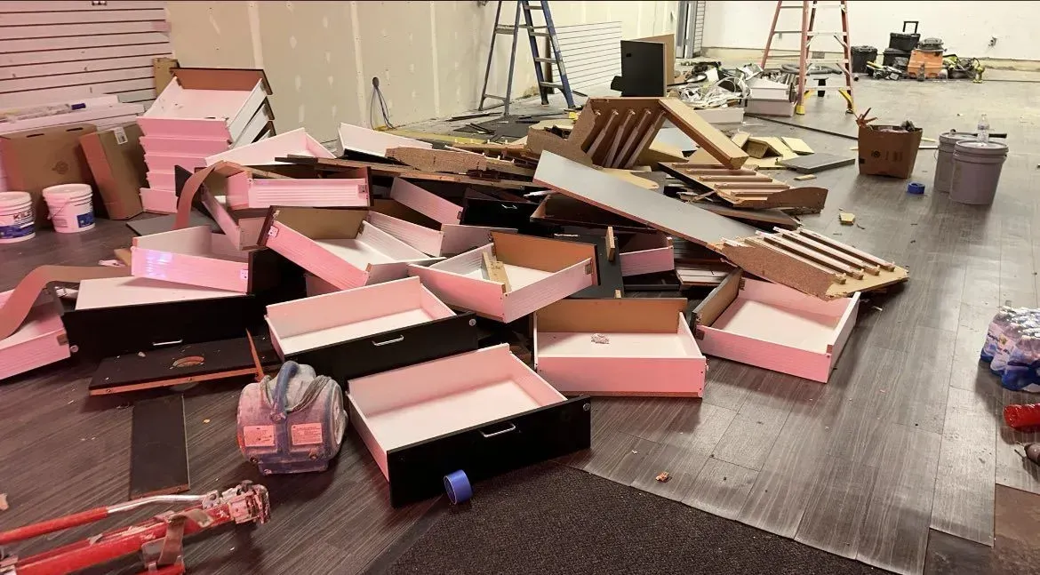Scattered pink foam panels and debris on a wet floor in an industrial workspace