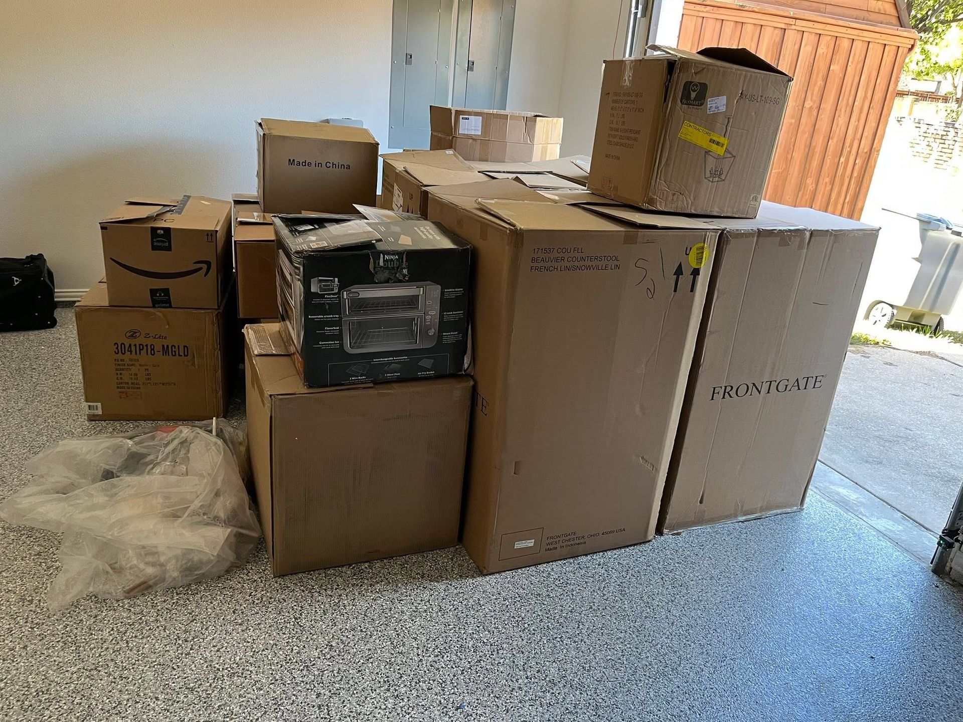 Stacked moving boxes and packing materials in a garage or carport.