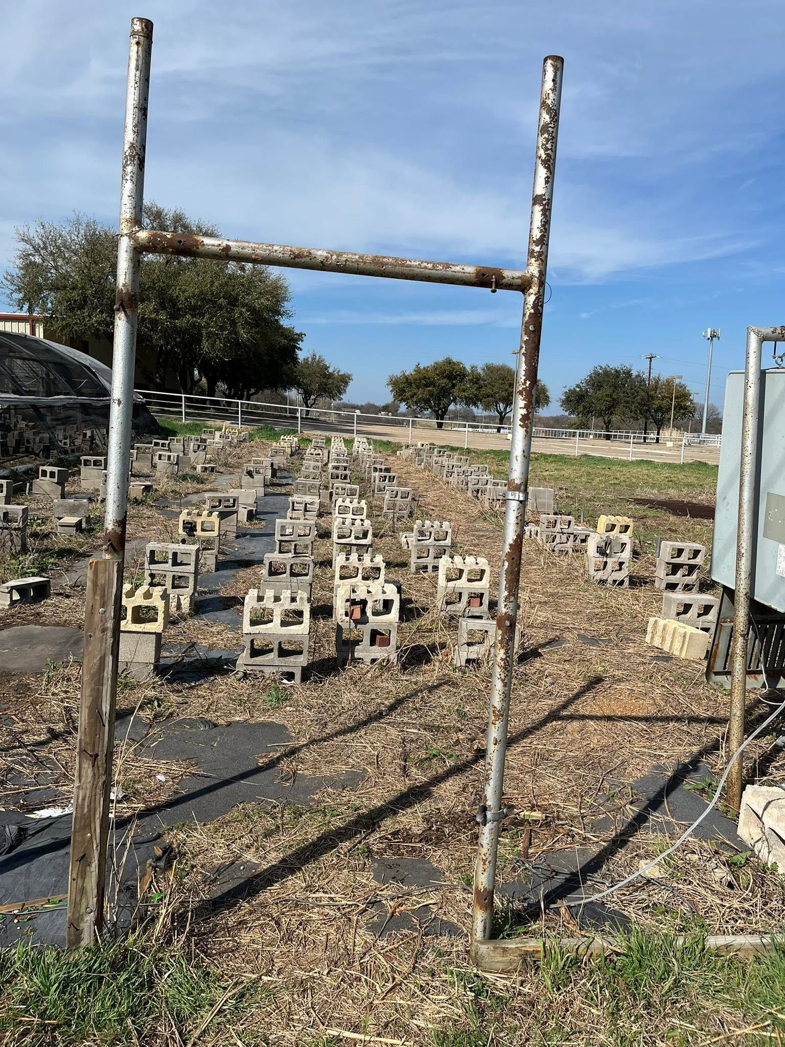 Weathered fence posts overlooking a hillside cemetery with rows of small grave markers under a blue sky