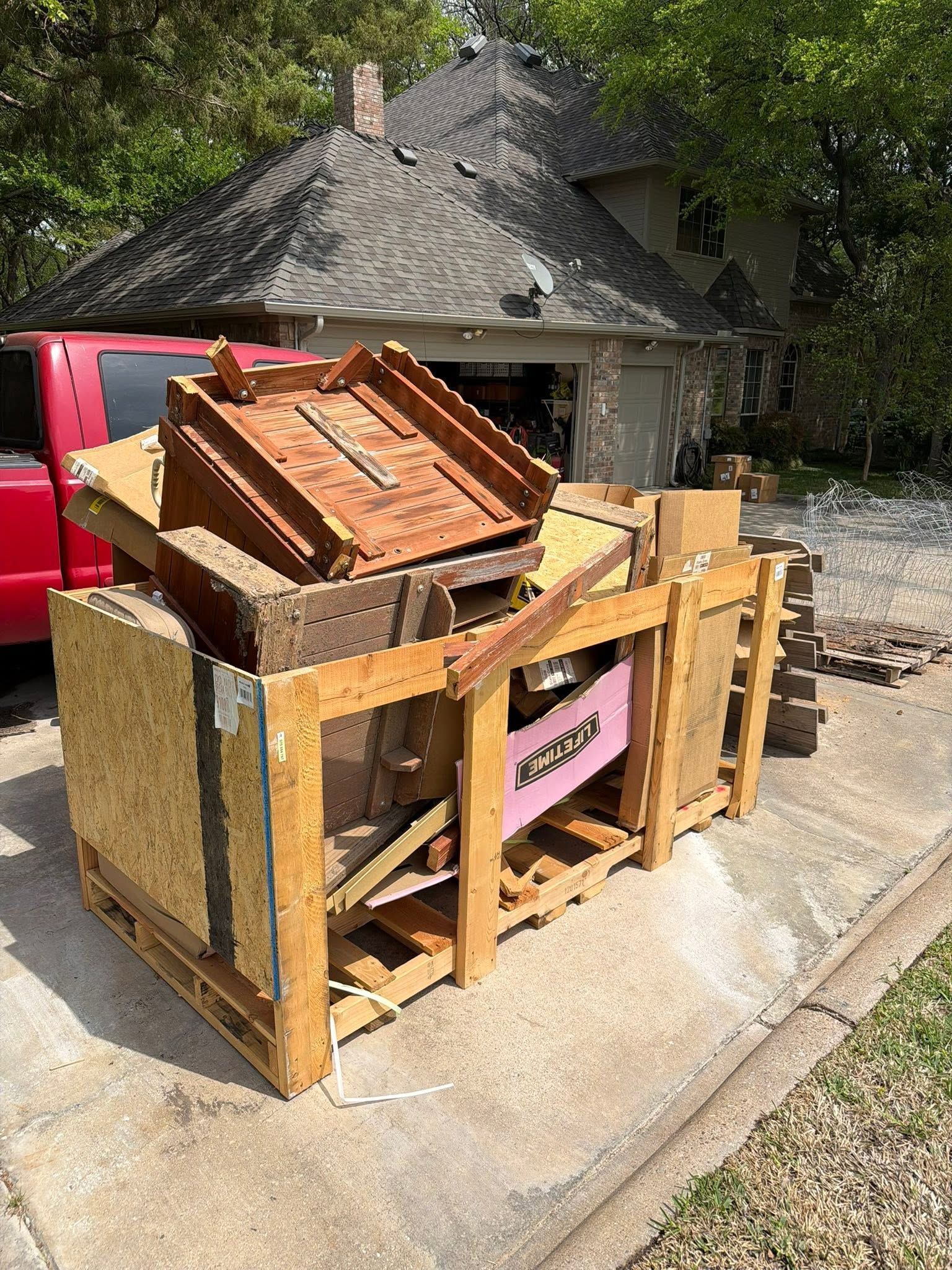 Wooden crates overflowing with broken furniture and debris at a curbside collection point.