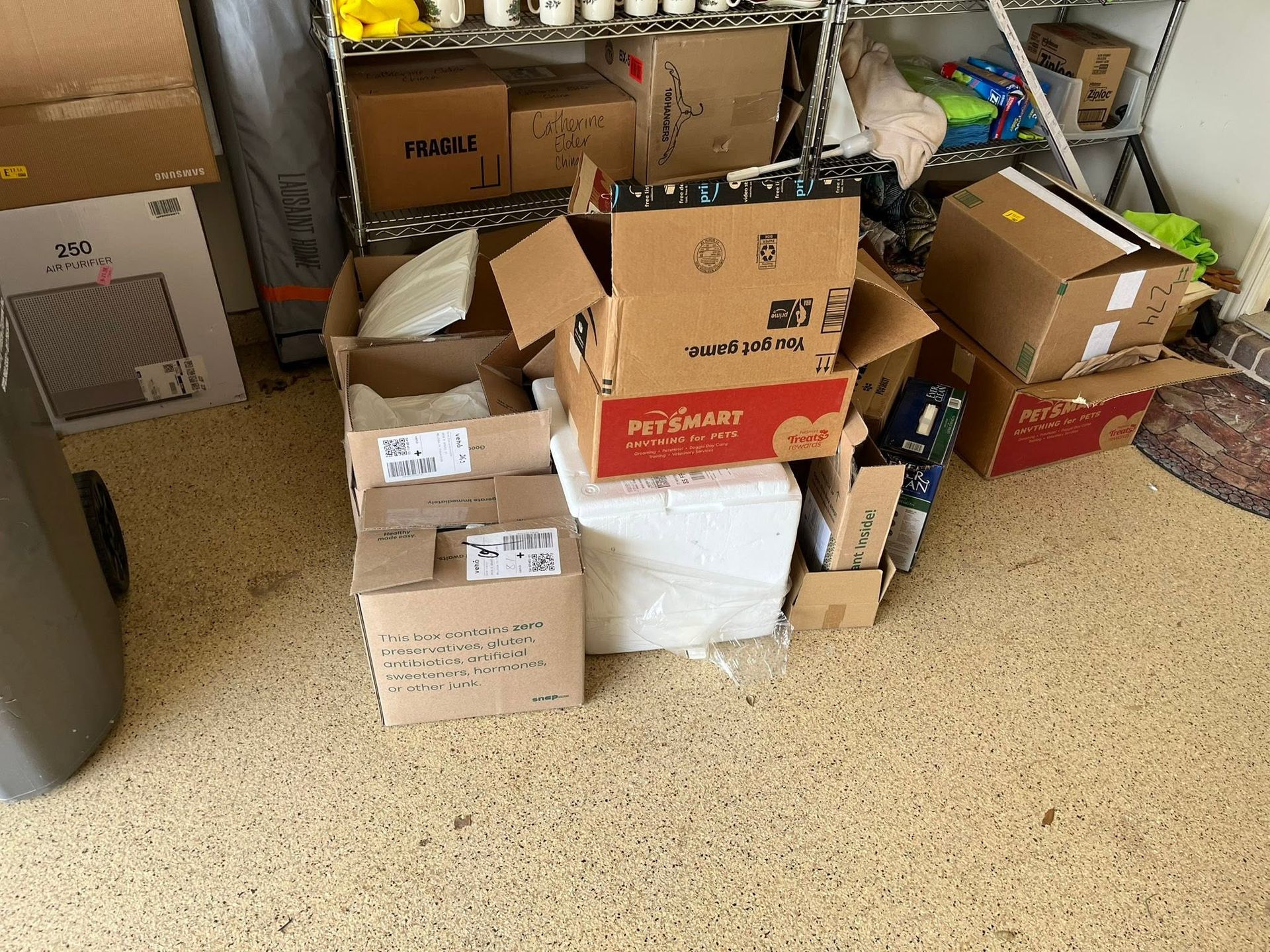 Stacked cardboard boxes in a cluttered storage area on a carpeted floor