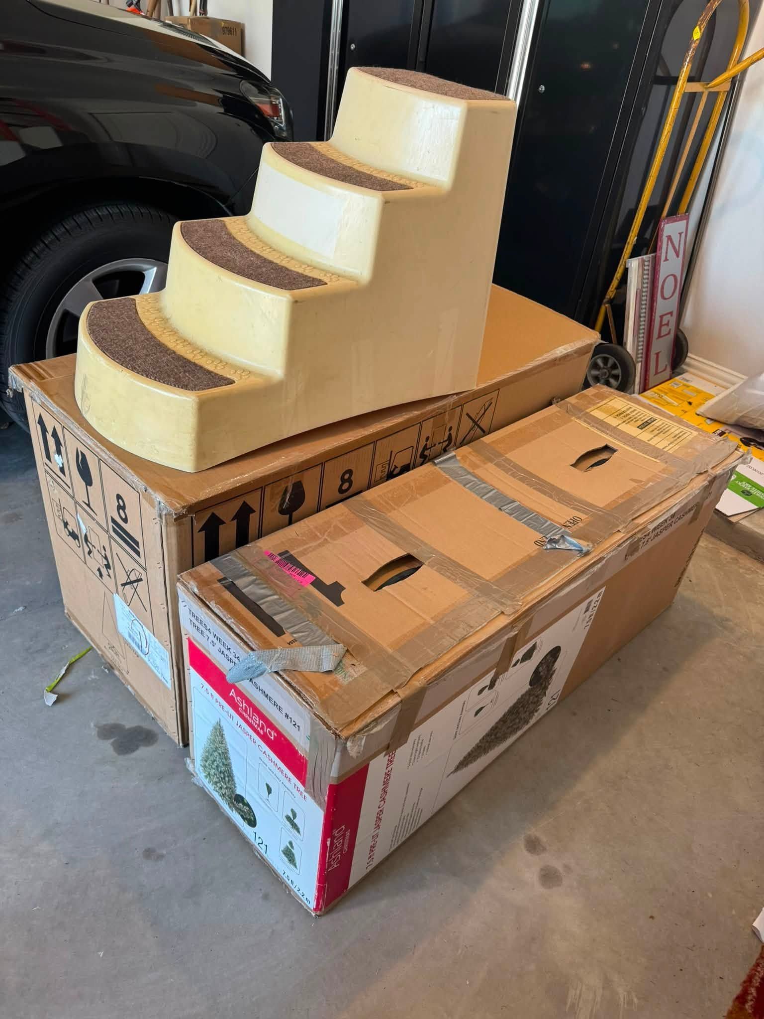 Foam stair mockup on cardboard boxes in a garage beside a car