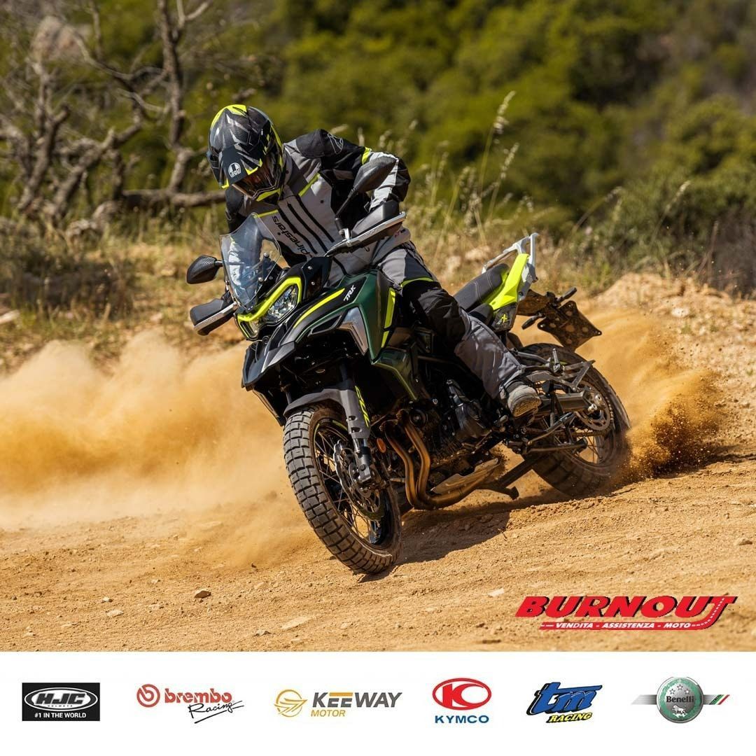 Un motociclista su una moto da cross verde e nera solleva polvere su una pista sterrata.