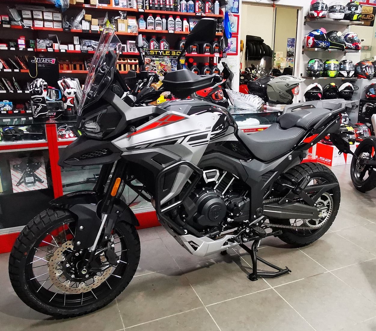 Motocicletta da avventura nera e argento parcheggiata all'interno di un negozio con caschi 
