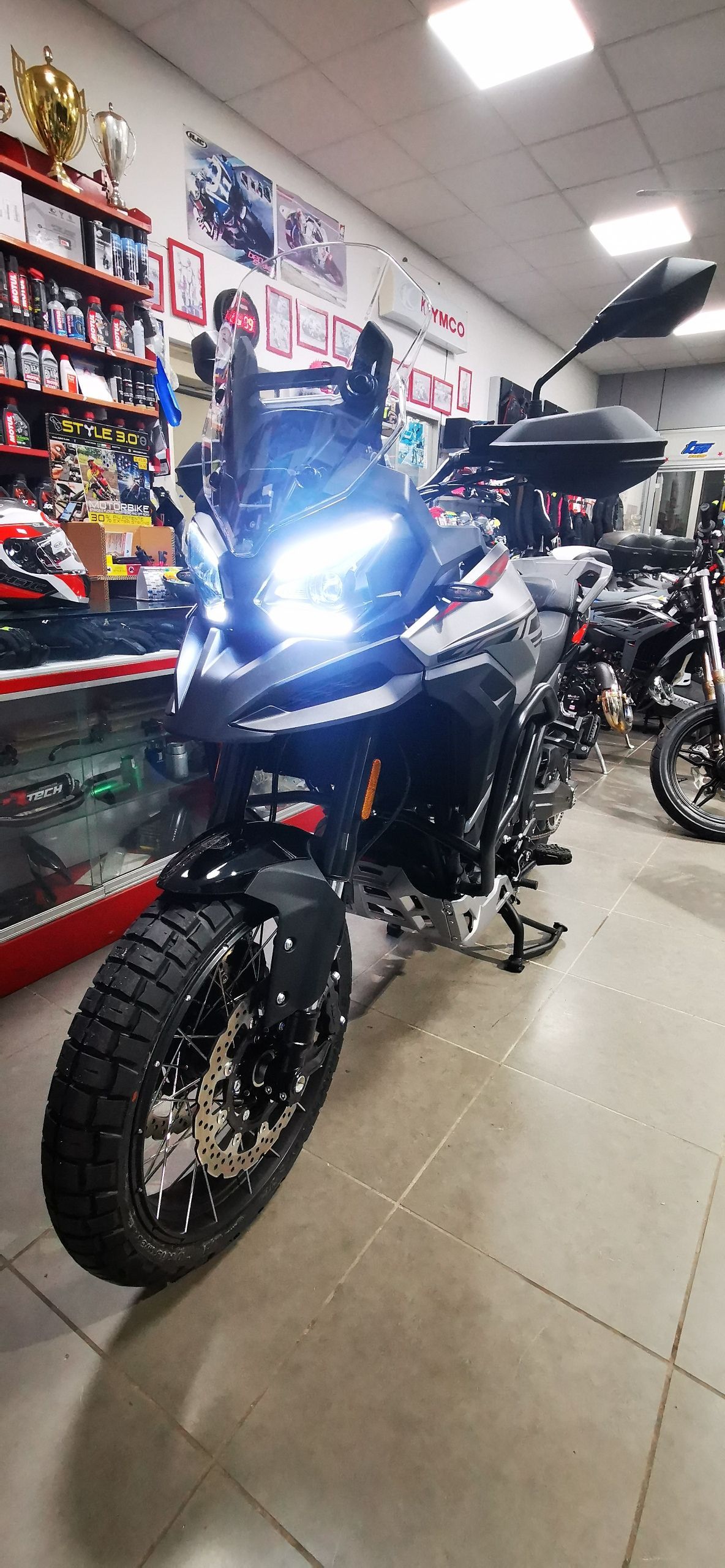 Una motocicletta nera con i fari accesi all'interno di un negozio.