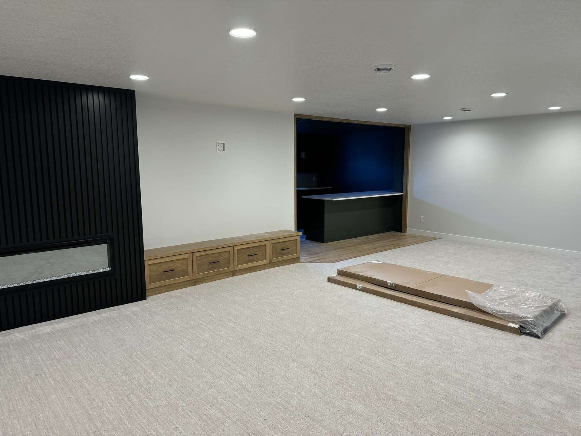 Empty room with carpet, black accent wall with fireplace, and built-in desk area.