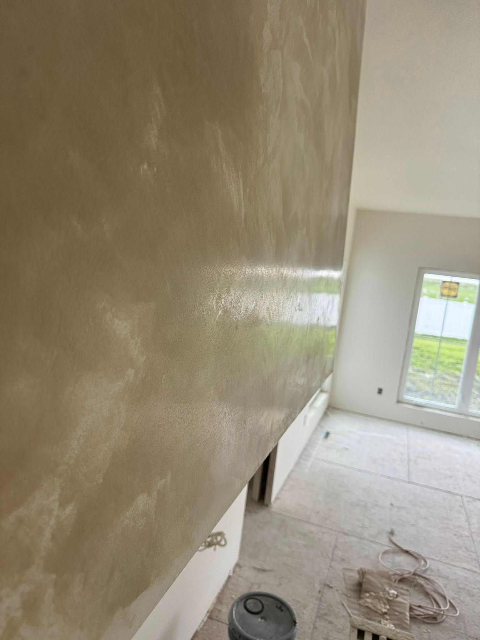 Textured beige wall with a subtle sheen, partially finished construction site.