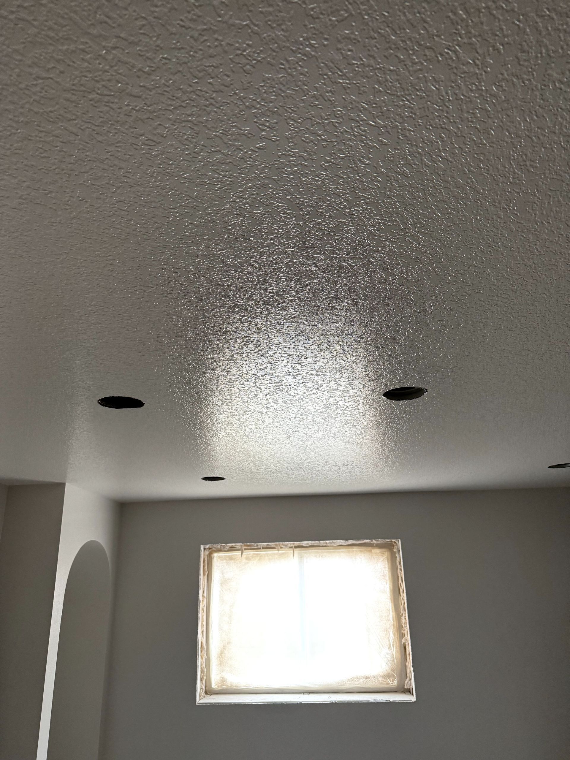 Room with freshly painted gray walls, unfinished floor, and a recessed ceiling light.
