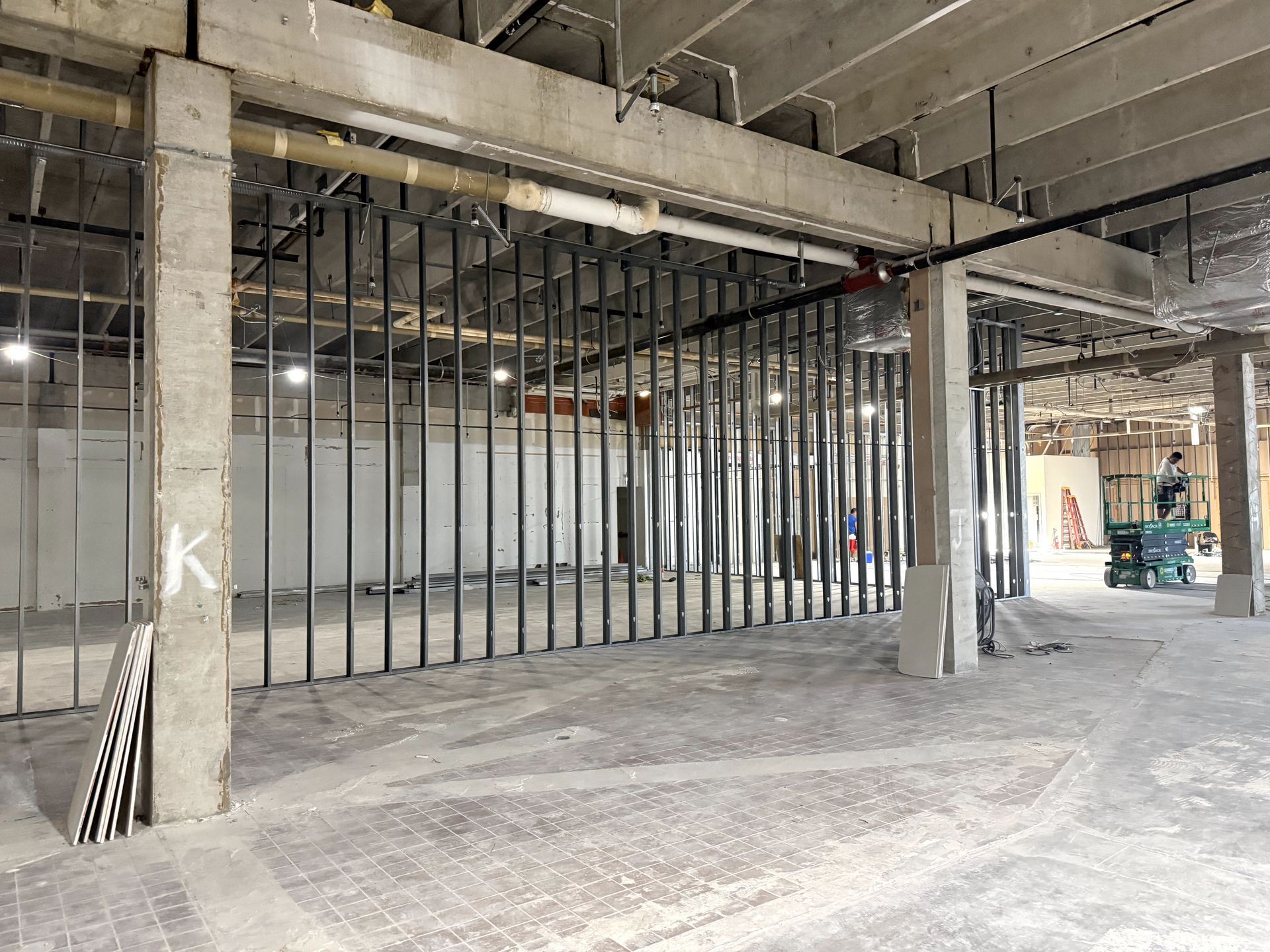 Construction site: room with a window, ladder, exposed ceiling beams, and debris on the floor.