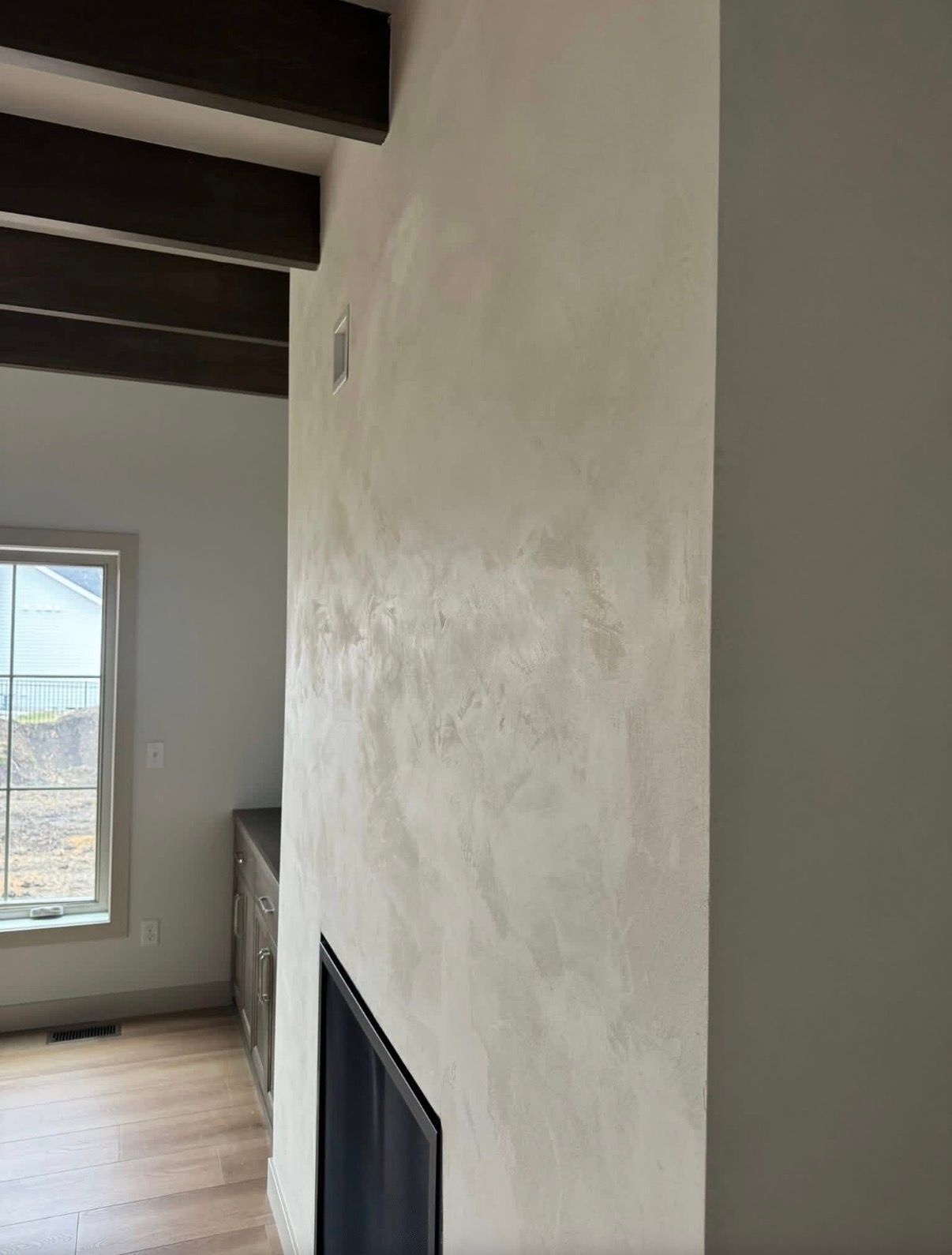 Man on a ladder spraying ceiling with a speckled texture. White walls, interior setting.