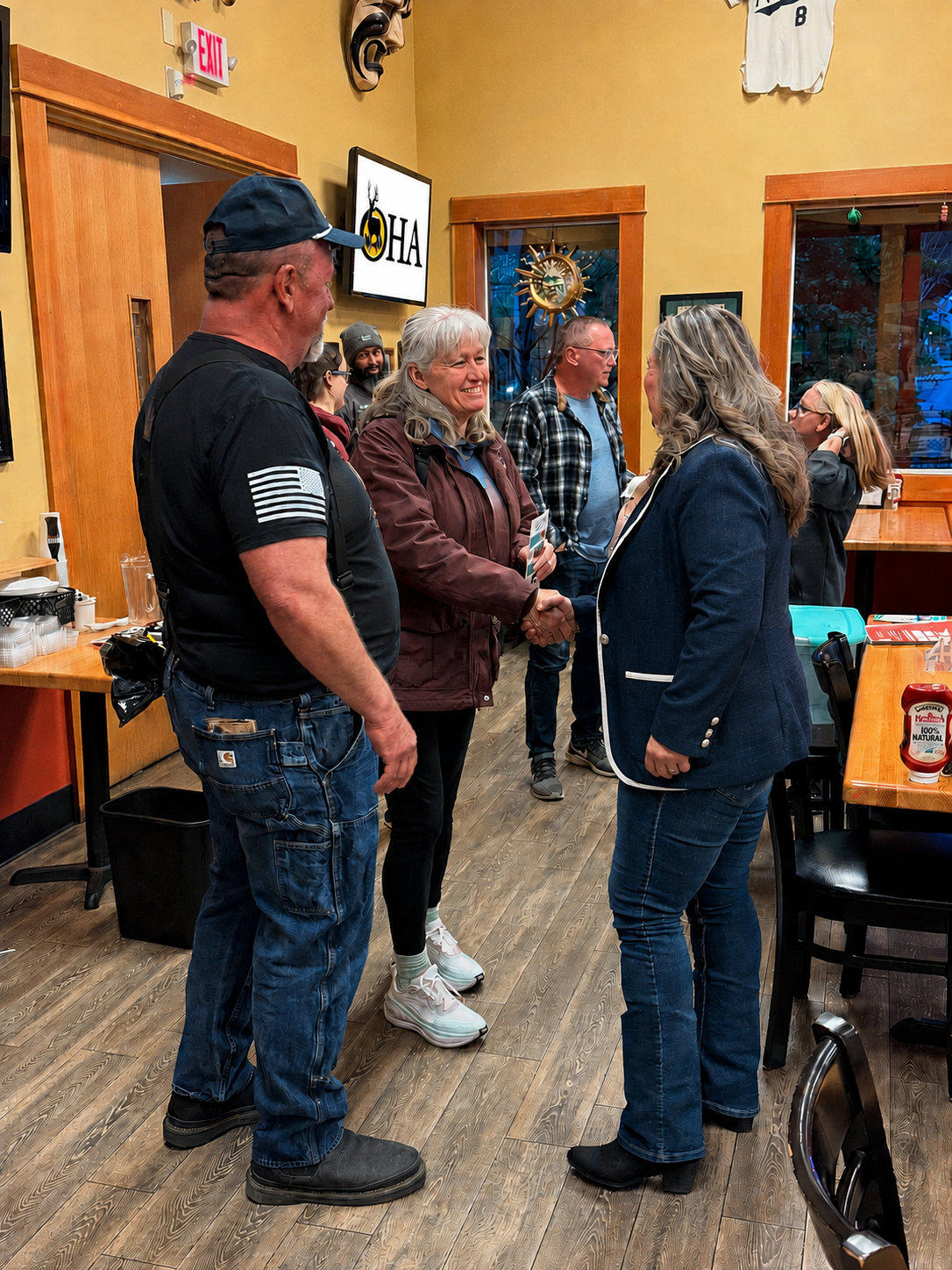 People chatting in a wood-paneled room during a small indoor gathering