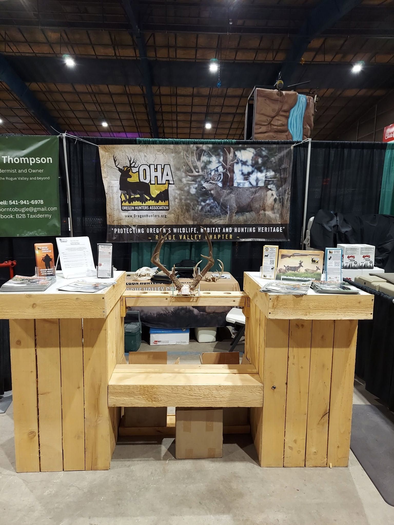 Wooden trade show booth with products and promotional banners in an indoor expo hall
