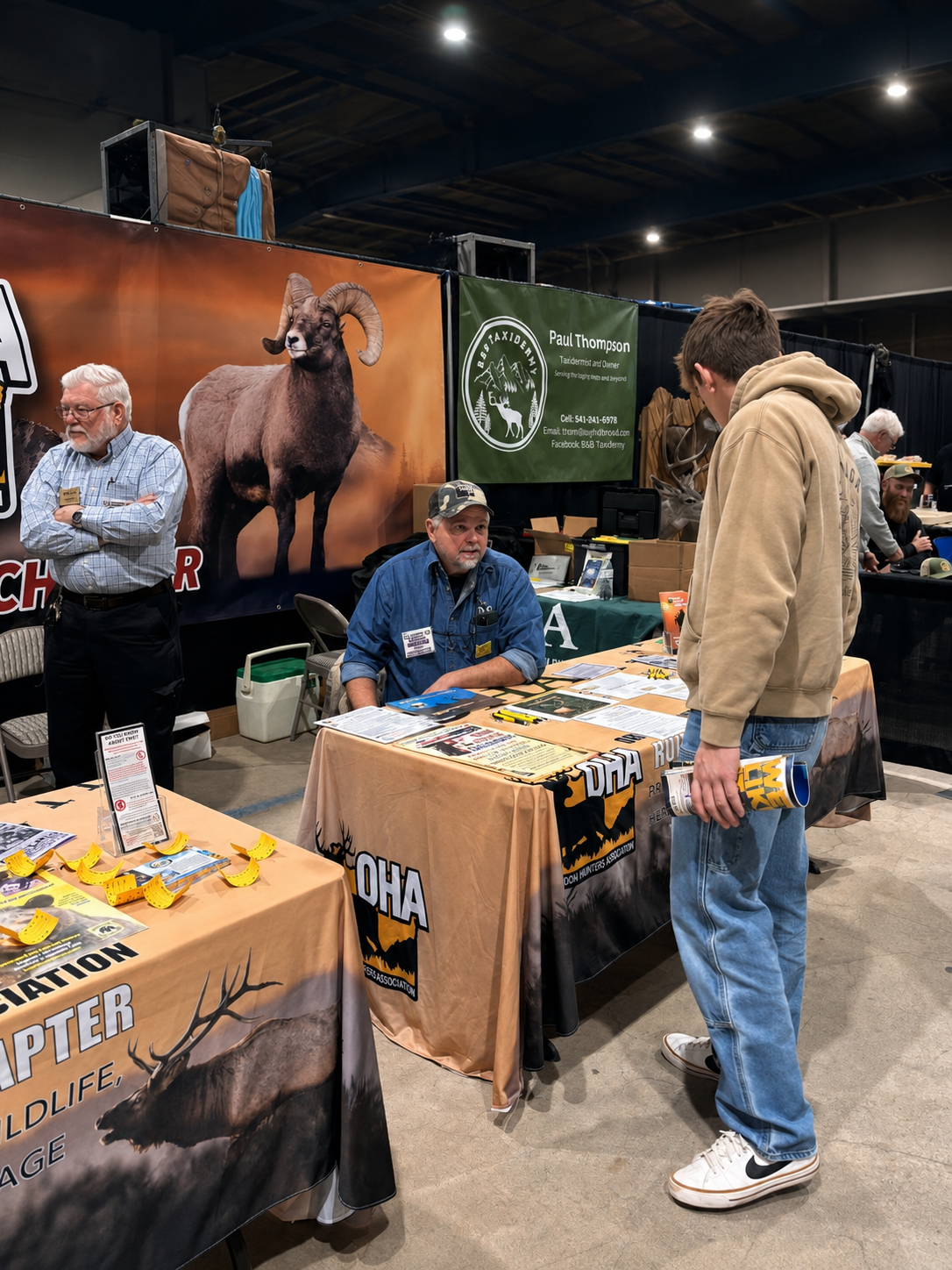 People browsing a horse-themed booth at an indoor expo, with banners, tables, and merchandise on display.