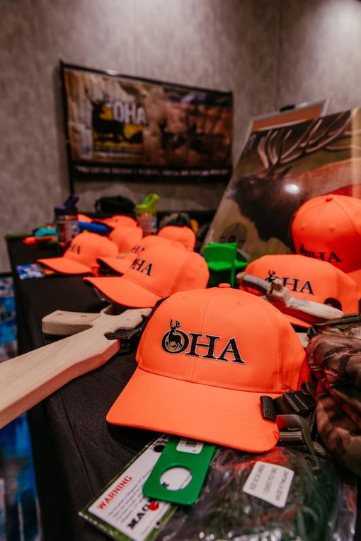 Orange hats with black logos displayed on a table in a room
