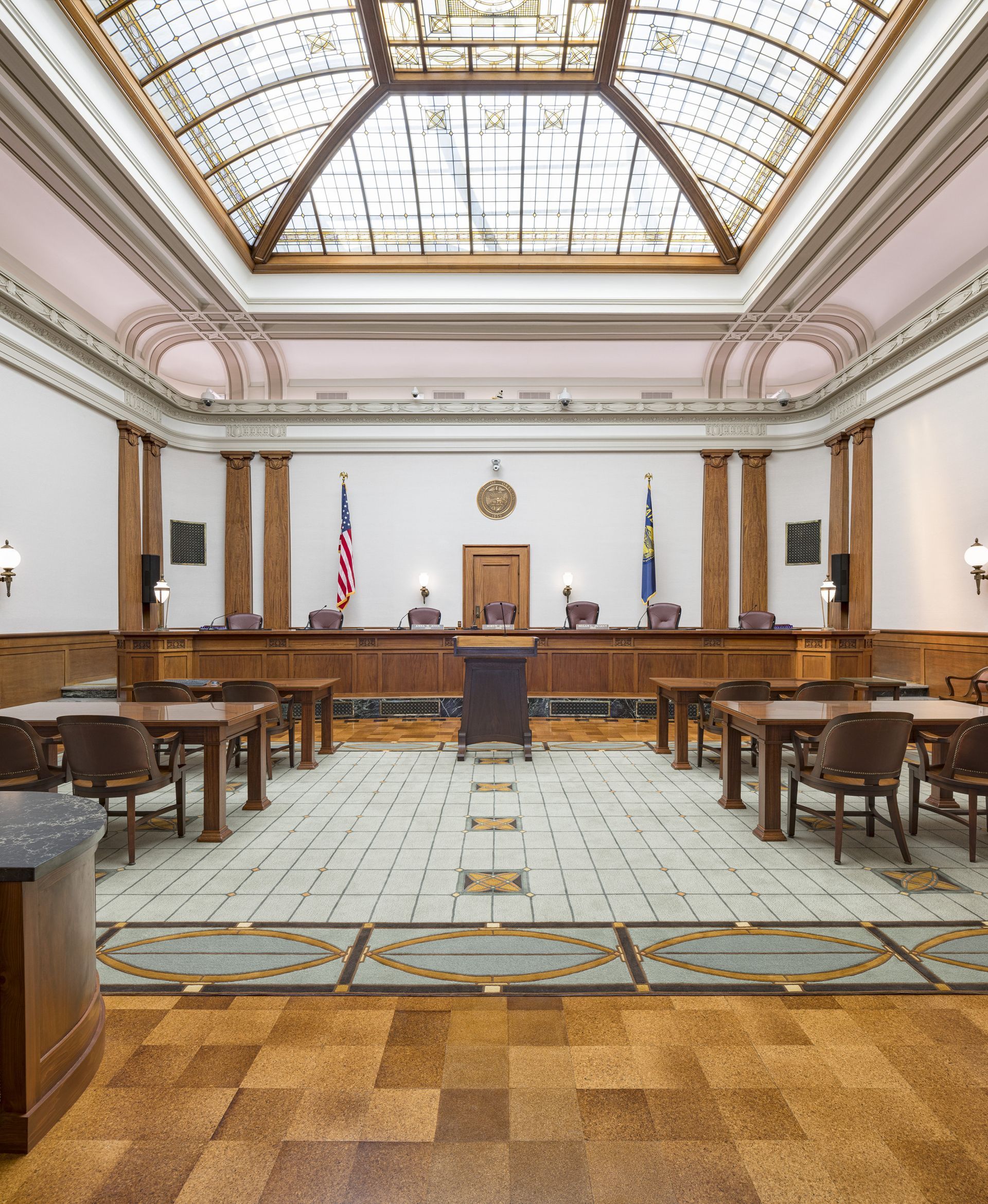 Courtroom interior with orange text reading “MEASURE 114 DECISION DELAYED?”