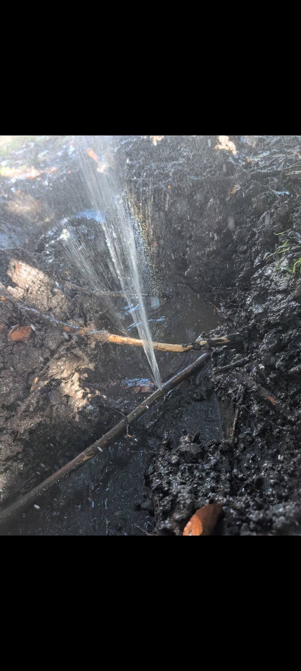 A Thin Stream of Water Sprays From a Leak in a Black Pipe — TasWide Plumbing in Kingston, TAS