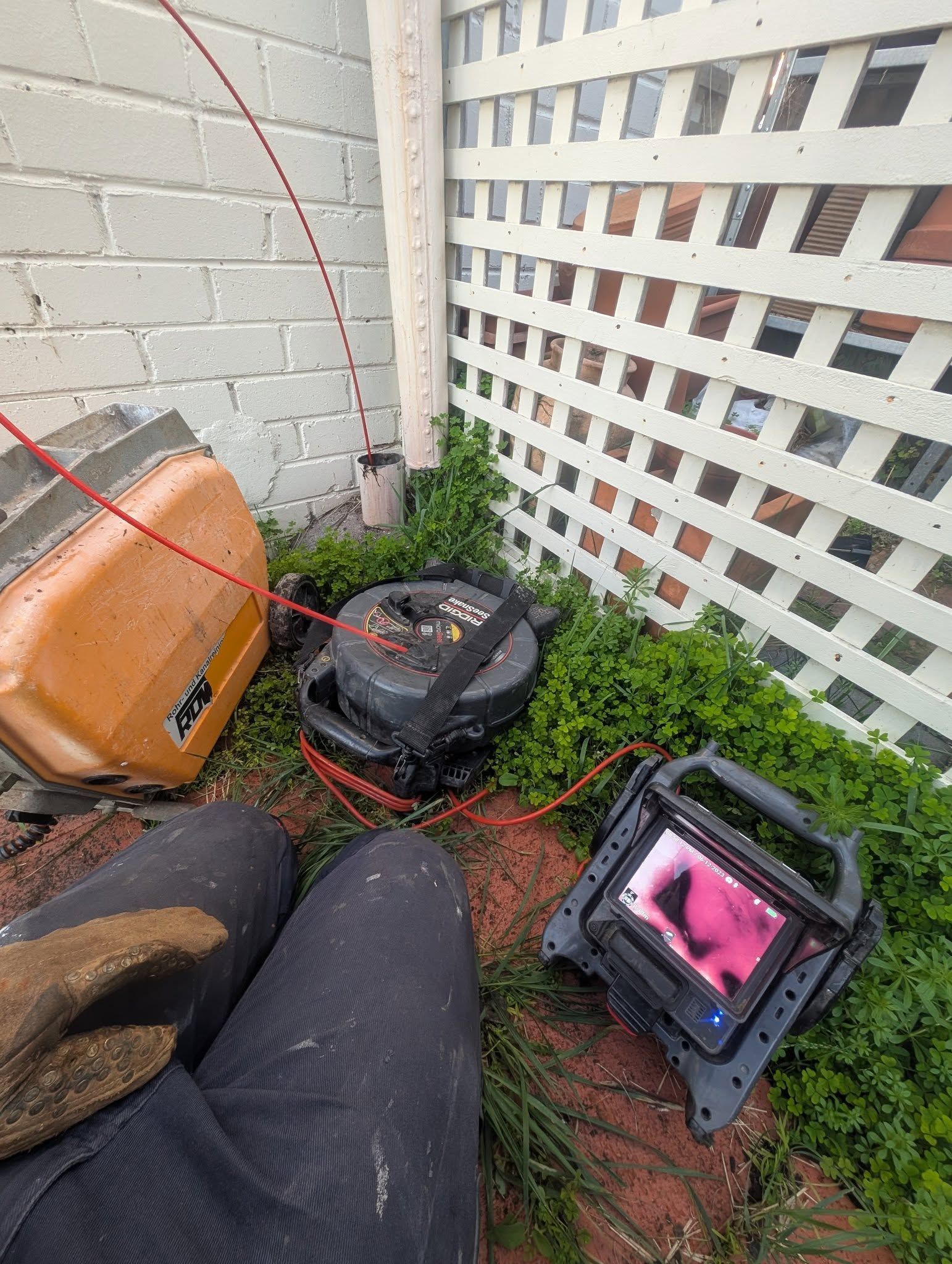 A Person Kneeling Outdoors Operates a Drain Inspection Camera System — TasWide Plumbing in Margate, TAS