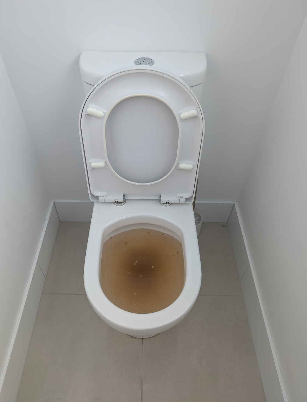 Open toilet with brown stained water in a small tiled restroom cubicle — TasWide Plumbing in Kingston, TAS