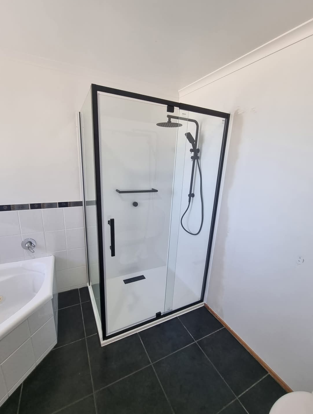 Modern bathroom with black-framed walk-in shower and white walls — TasWide Plumbing in Kingston, TAS