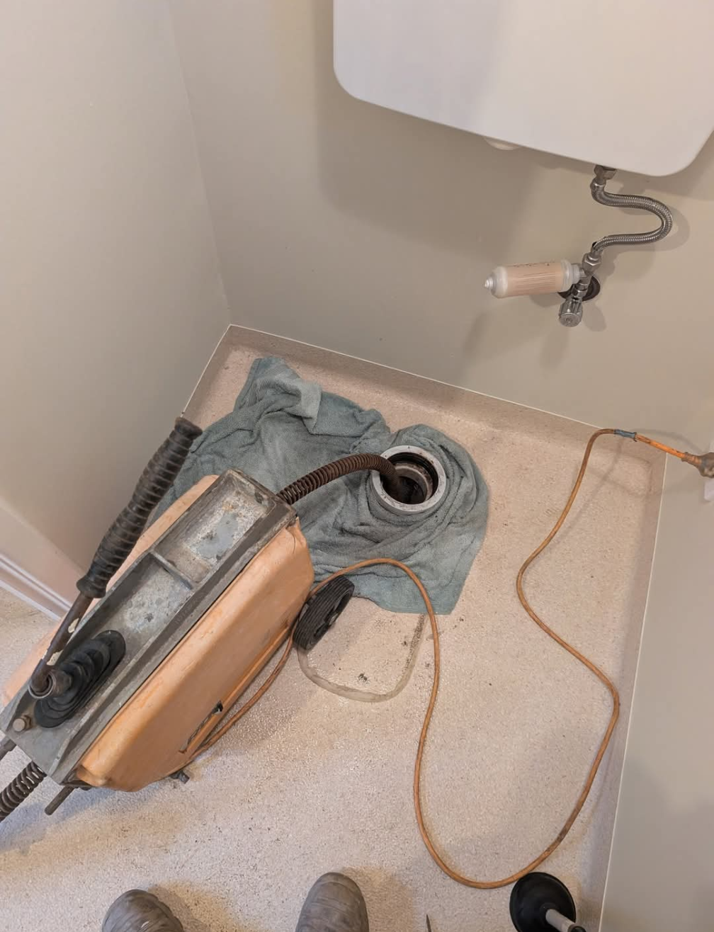 Broken vacuum cleaner on a bathroom floor beside a sink and drain hose. — TasWide Plumbing in Kingston, TAS