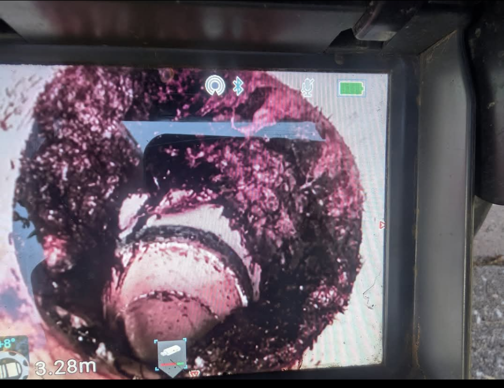 Close-up of a muddy circular pipe interior with dark debris and pink residue, seen on a camera screen — TasWide Plumbing in Kingston, TAS