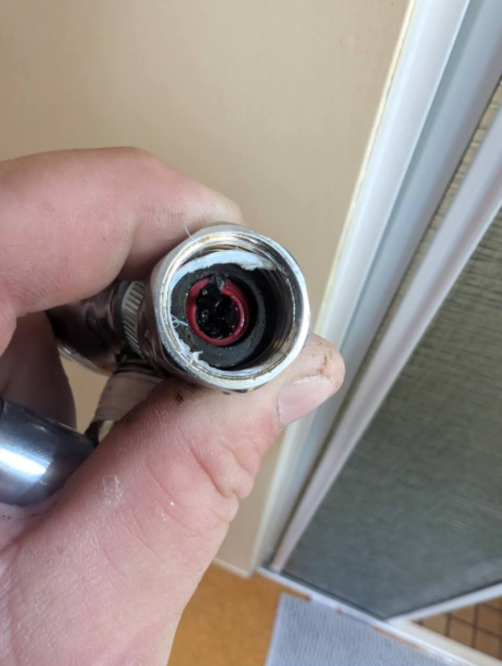 Close-up of a hand holding a metal hose fitting with a red inner ring. — TasWide Plumbing in Kingston, TAS