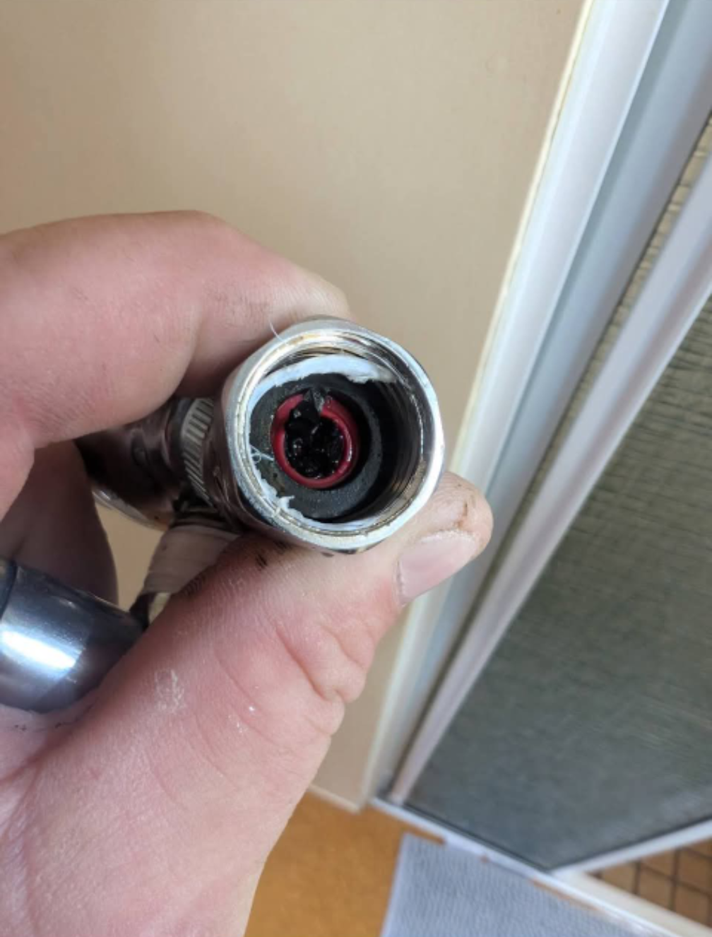 Hand holding a damaged cable end with a red inner wire exposed near a doorway — TasWide Plumbing in Kingston, TAS