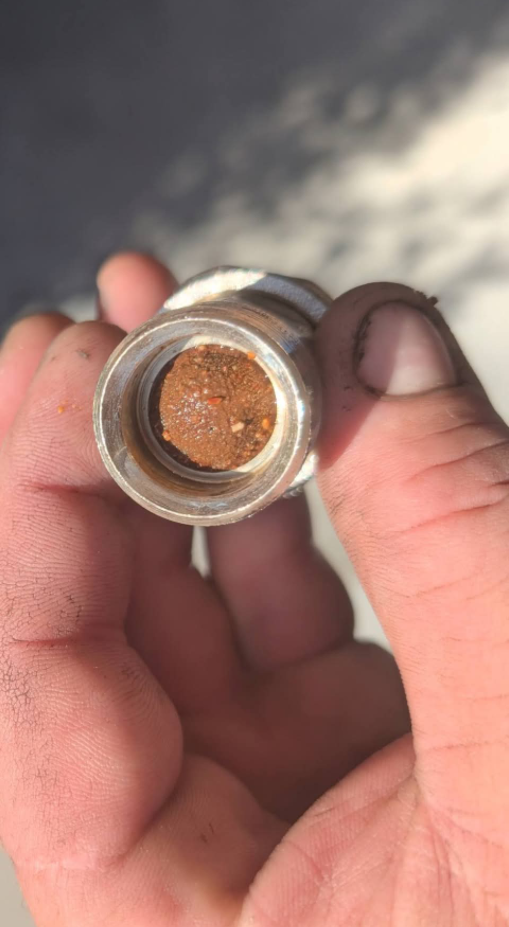 Hand holding a small metal cap with a copper-colored, textured center in sunlight — TasWide Plumbing in Kingston, TAS