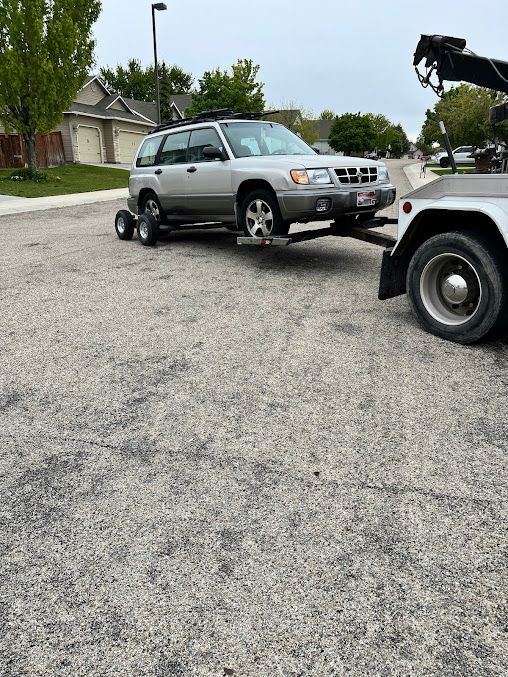 A silver suv is being towed by a tow truck.