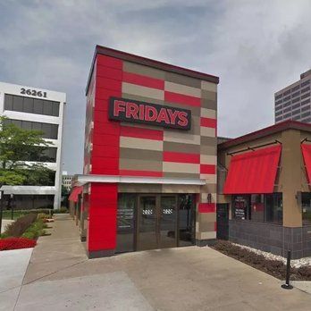 TGI Fridays restaurant storefront with red and gray exterior and glass entrance under cloudy sky