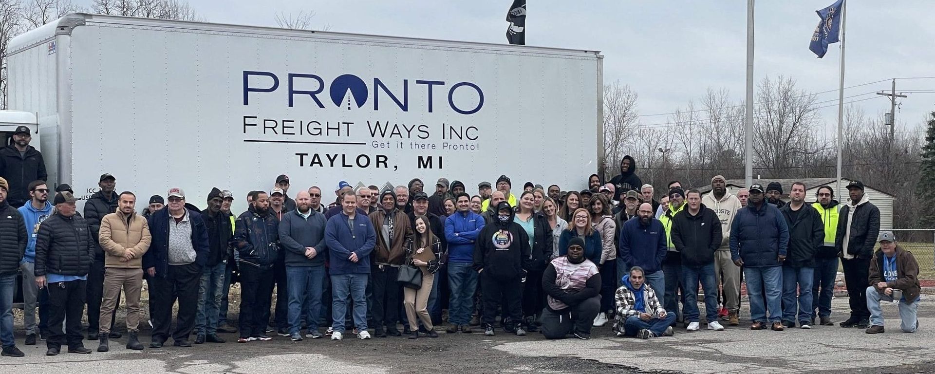 Group of people posing in front of a PRONTO sign at Taylor, MI facility