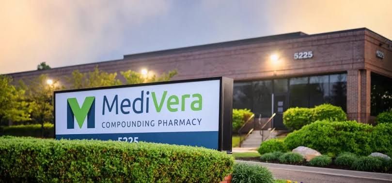 MediVera Compounding Pharmacy storefront with green logo and landscaped entrance at dusk
