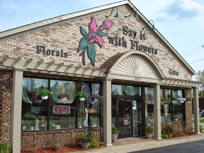 Flower shop storefront with sign “Say It With Flowers,” floral mural, and large front windows