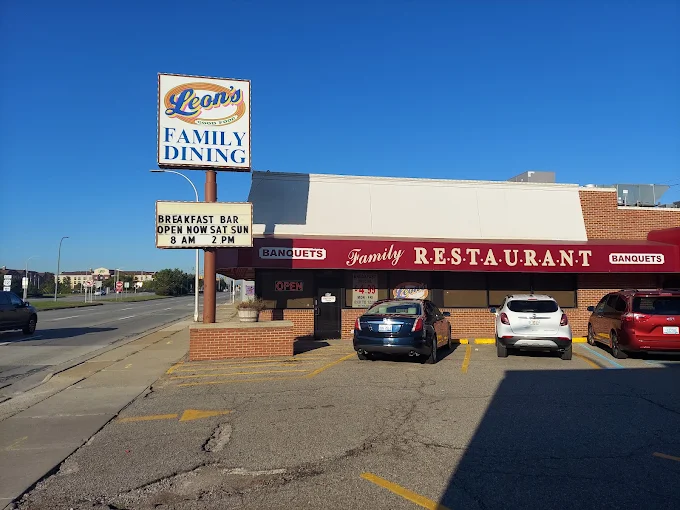 Leon's Family Dining restaurant storefront with parking lot and cars on a sunny street.