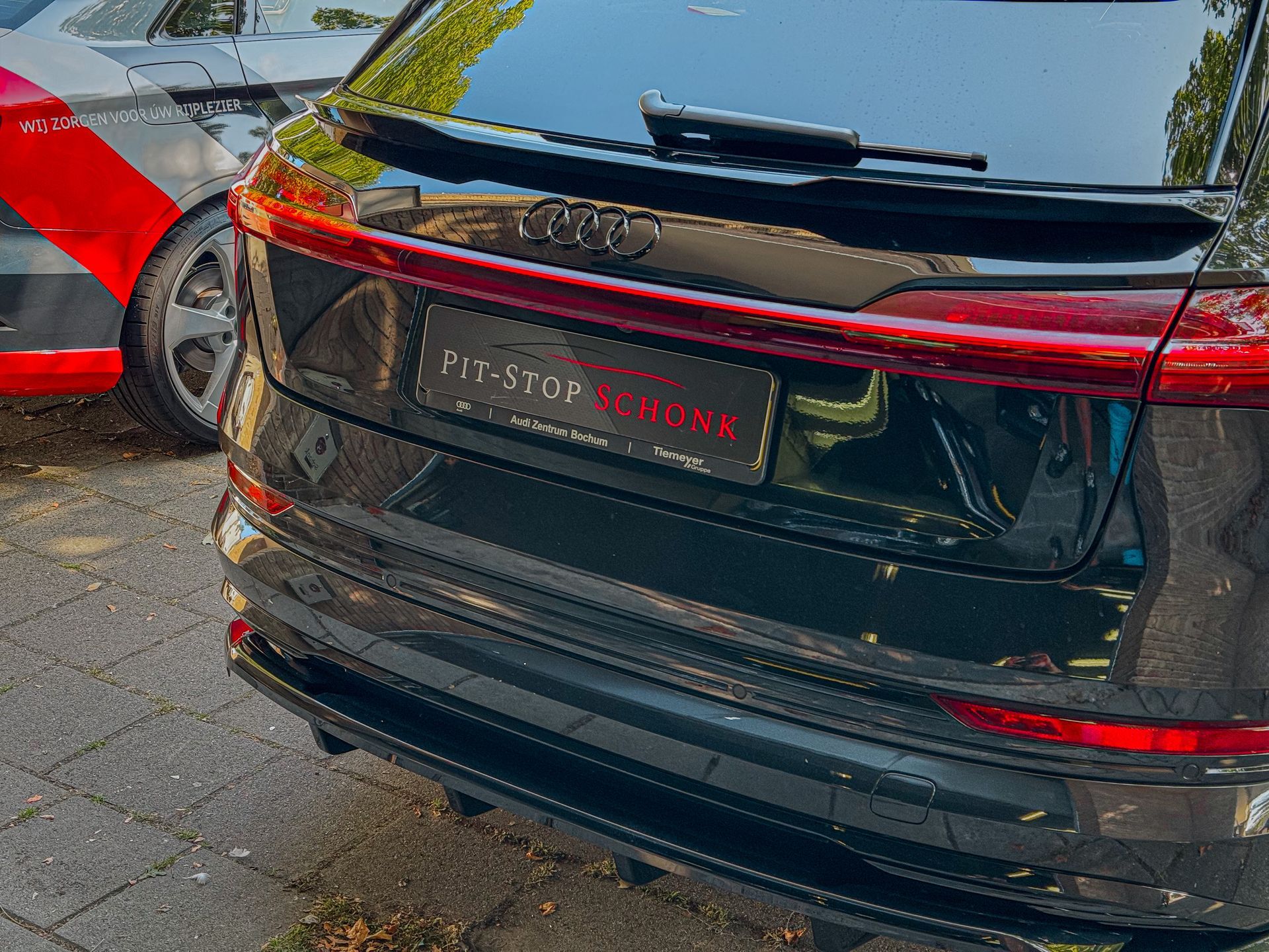 Een zwarte auto staat geparkeerd naast een rode auto