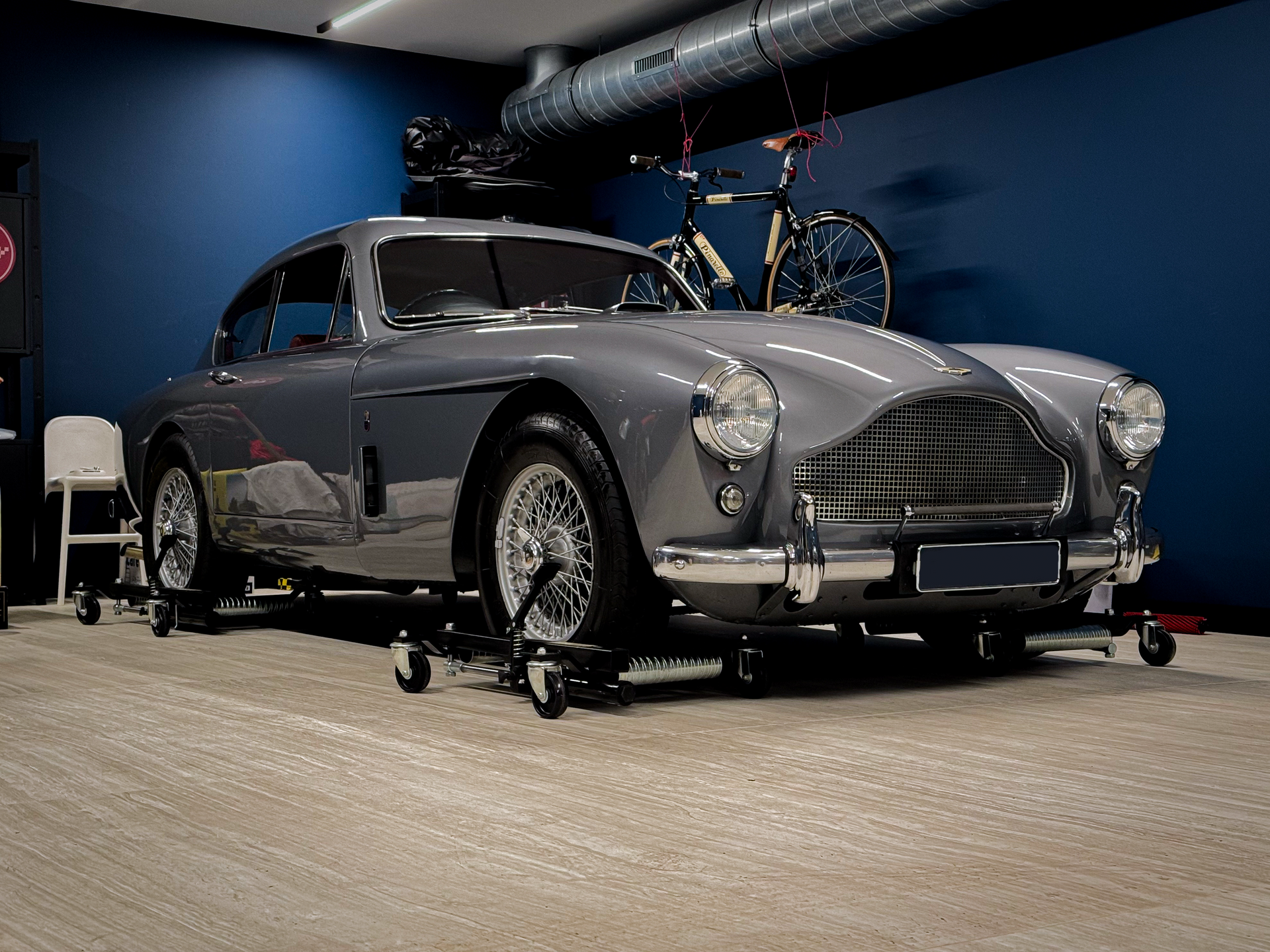 Een grijze auto staat geparkeerd in een garage naast een fiets.