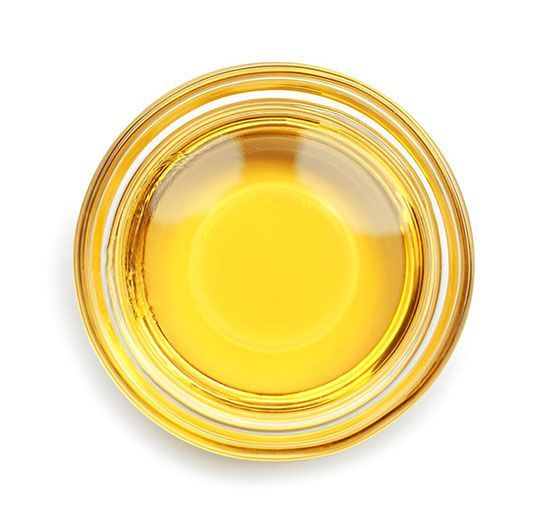 Top-down view of a clear glass filled with yellow liquid on a white background