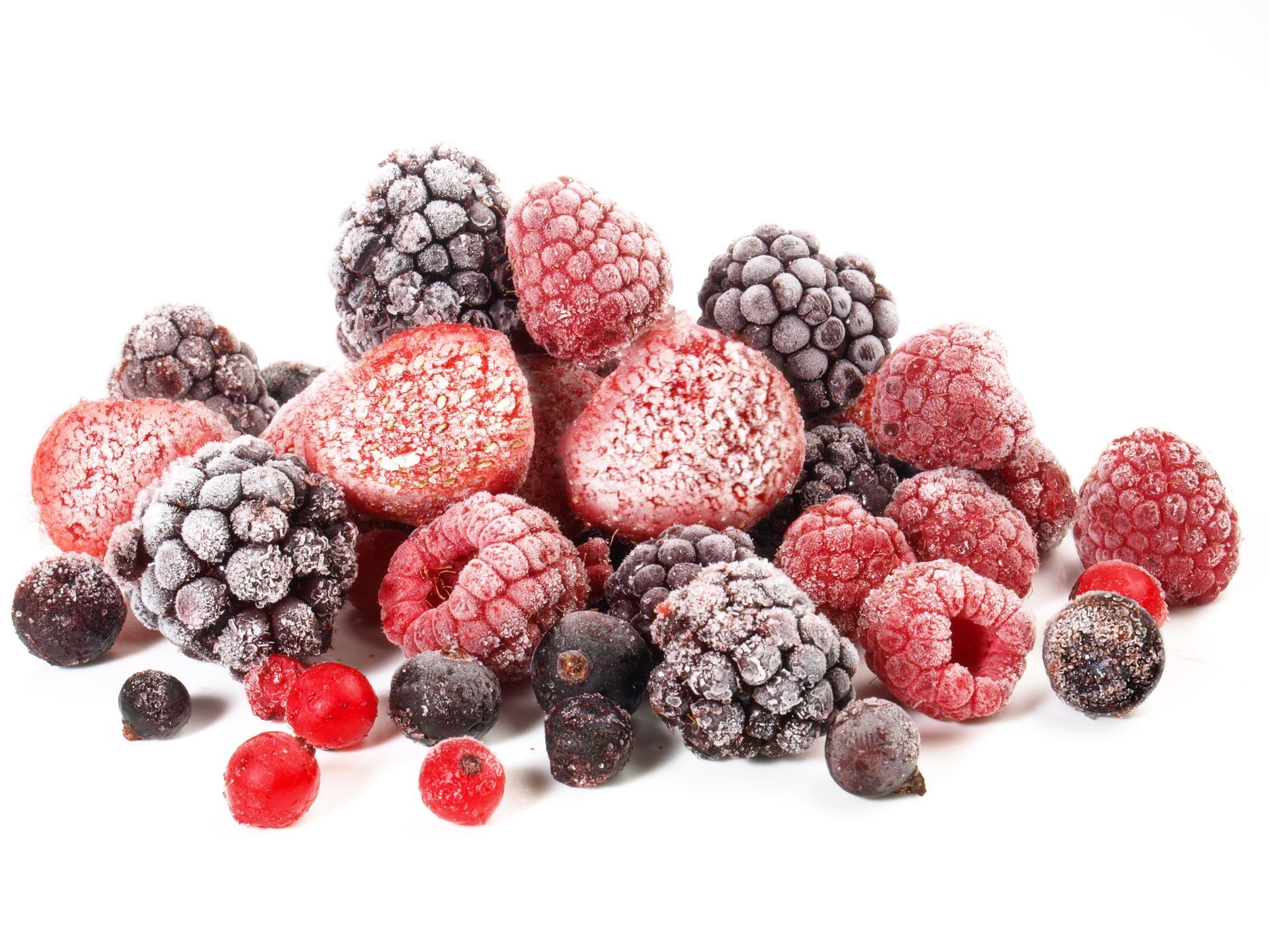 Frozen mixed berries piled on a white background, including raspberries, blackberries, and strawberries